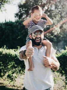 a father carrying his son over his shoulders