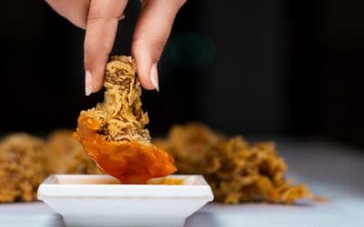 person dipping fried chicken in sauce